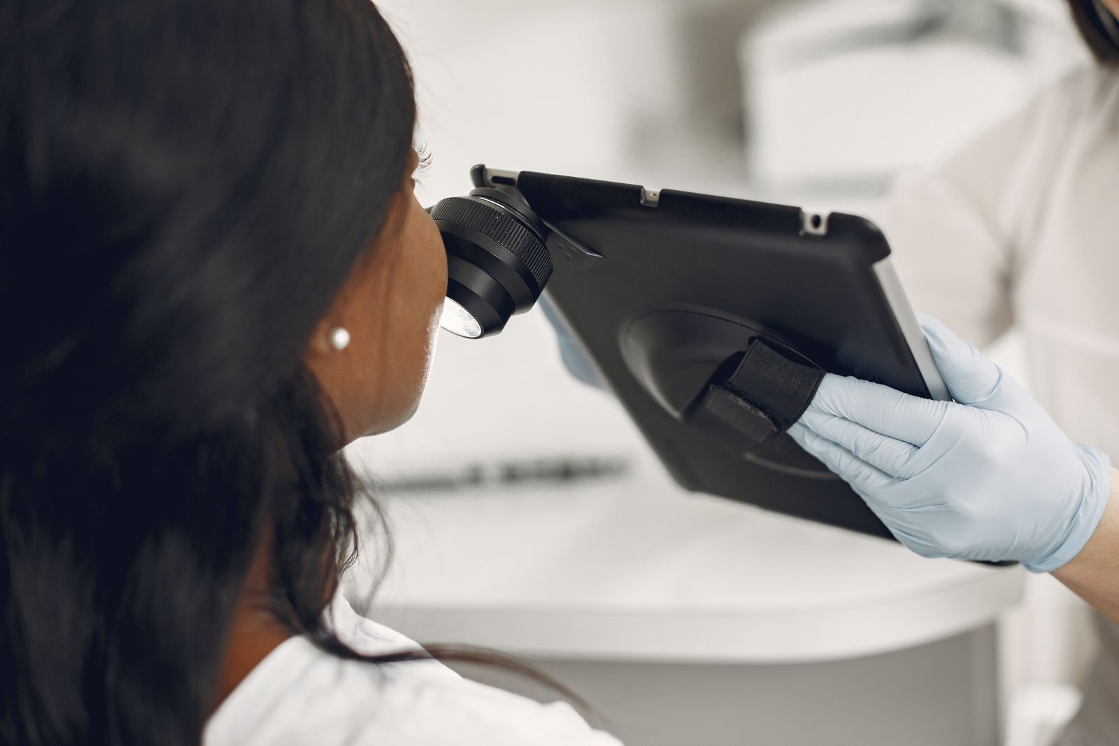 Dermatologist examining a patient's skin with a digital dermatoscope attached to a tablet
