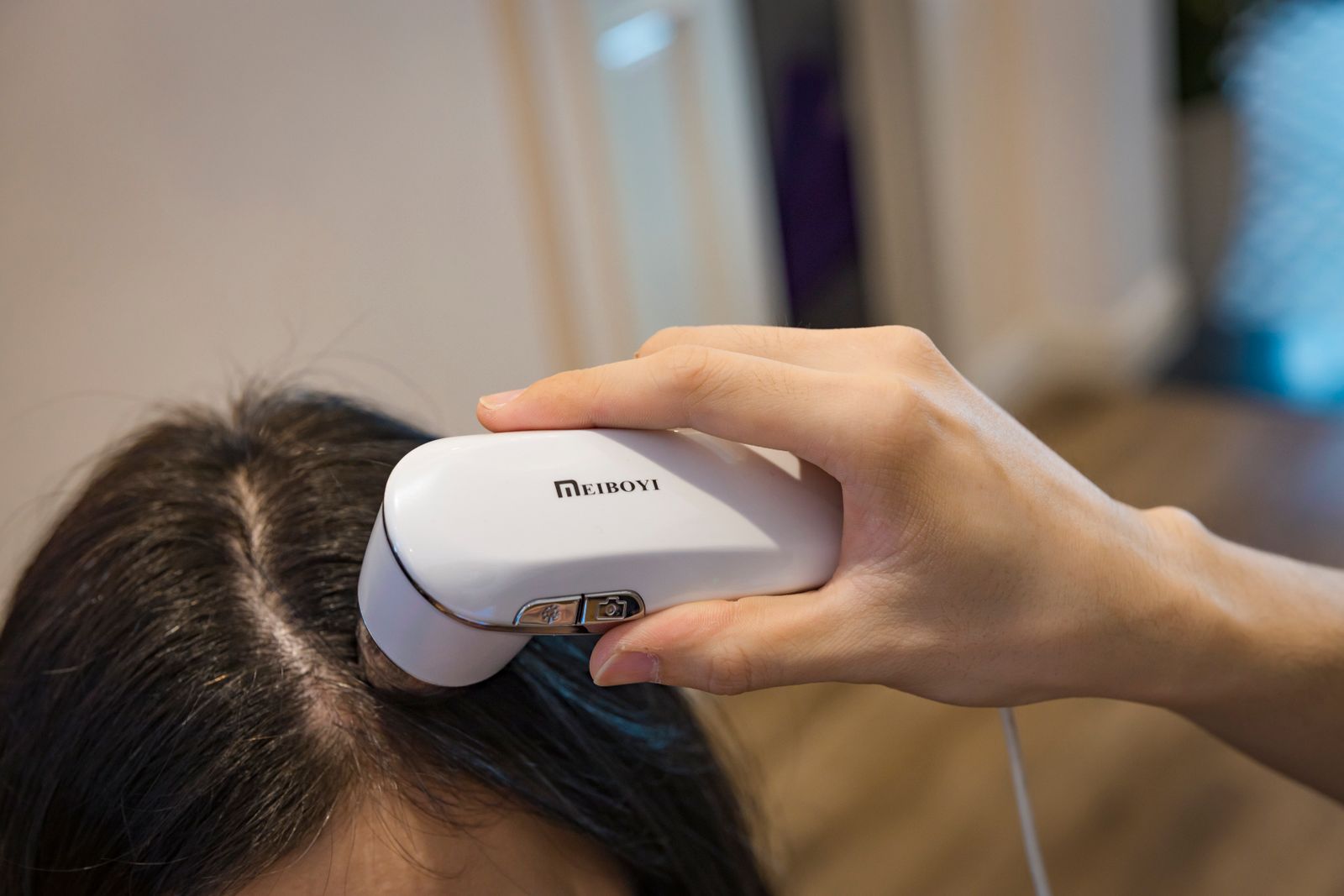 Handheld scalp-analysis device being used on a patient's scalp during a trichoscopy exam